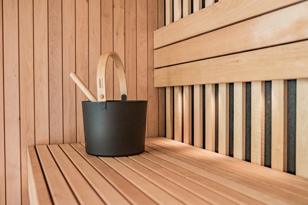a wooden sauna with a black bucket and two wooden spoons