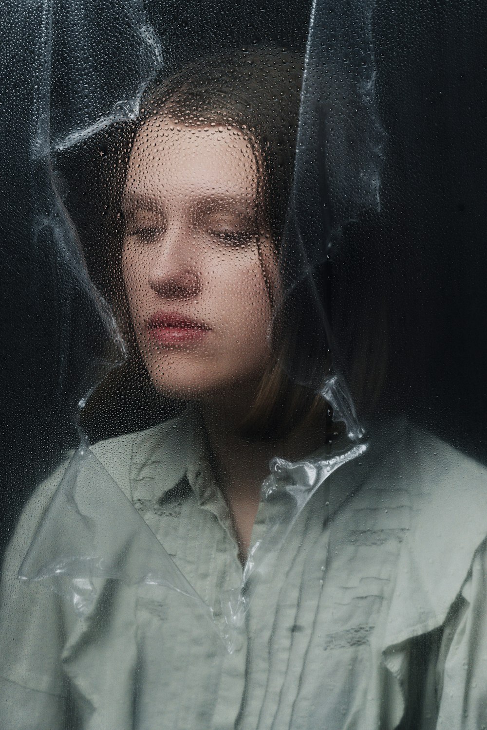 a woman with her eyes closed standing in front of a window