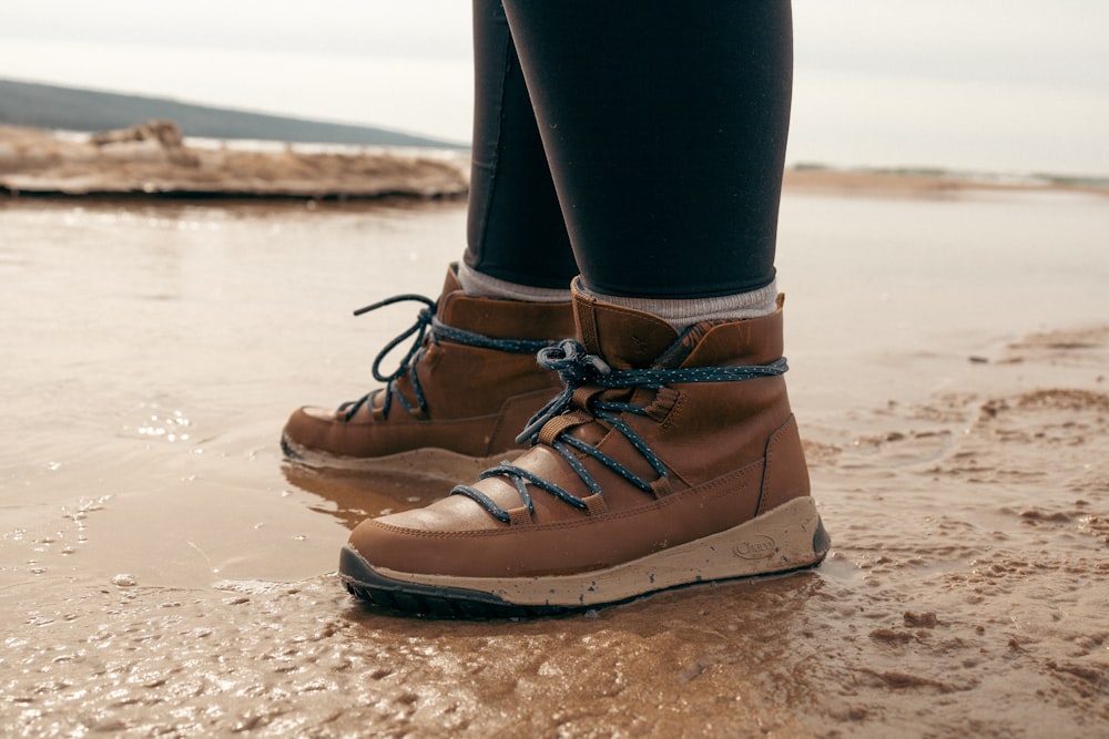 a person standing on a beach wearing brown shoes