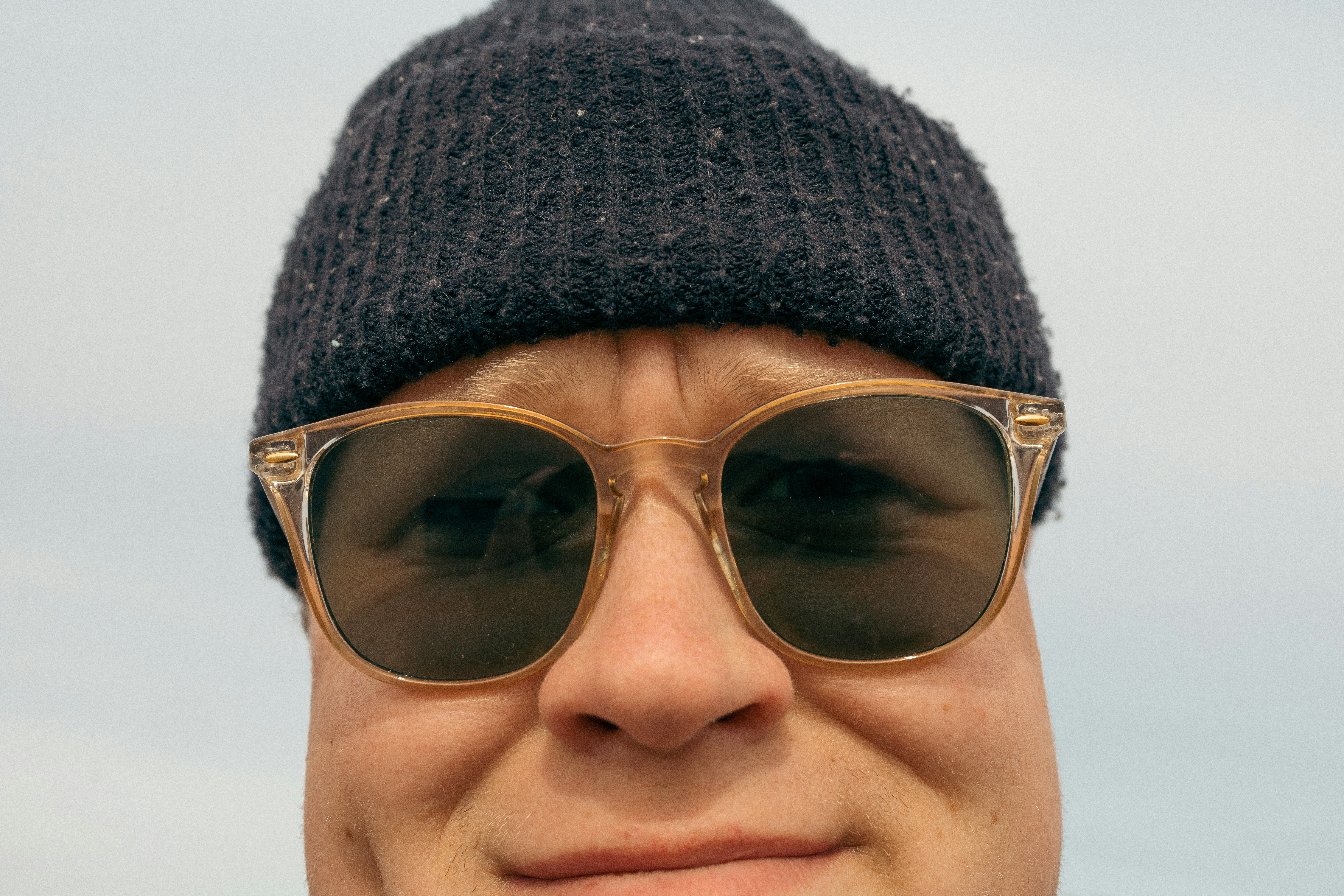 Person wearing beanie hat outdoors, natural daylight, urban street backdrop
