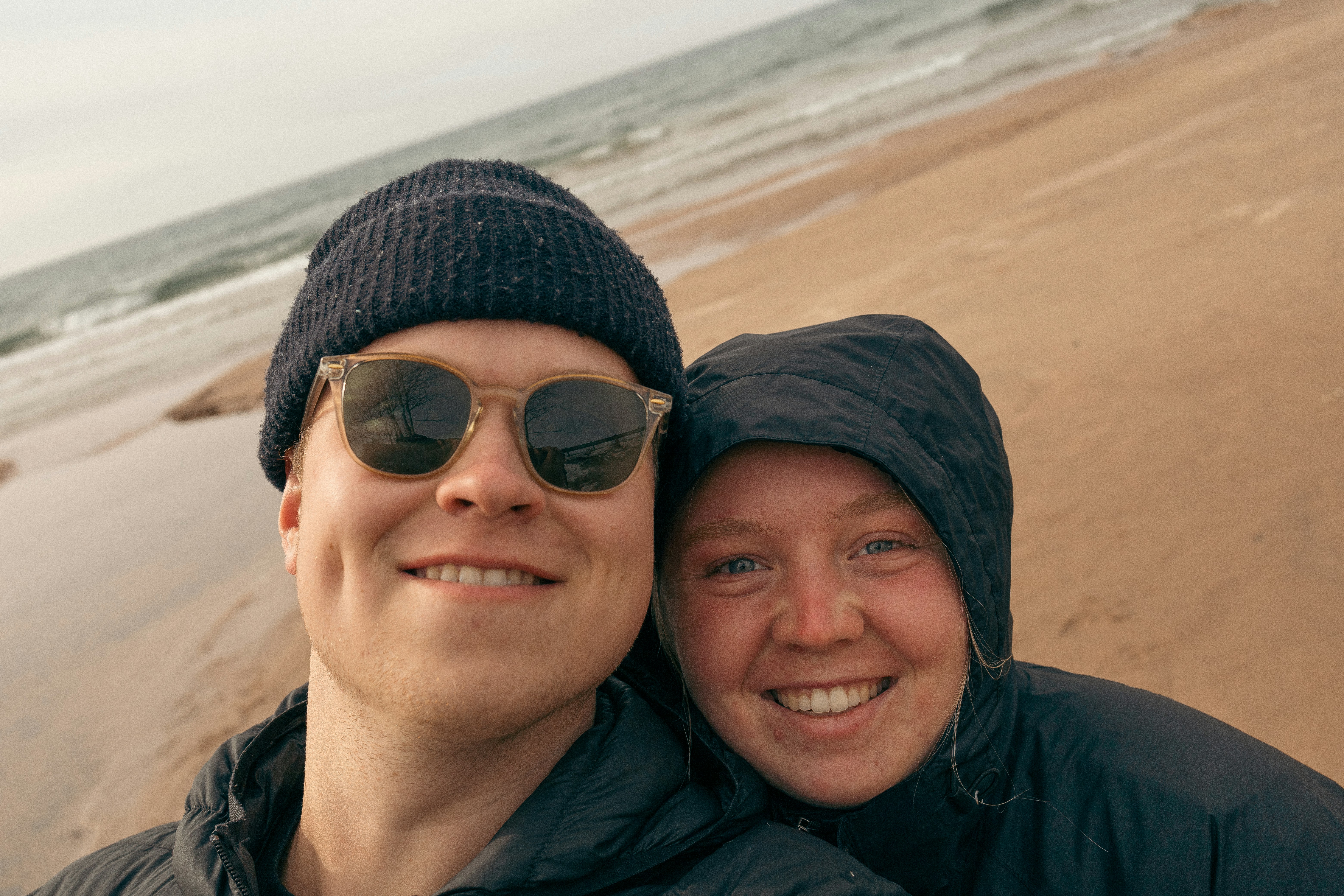 a man and a woman standing on a beach next to the ocean