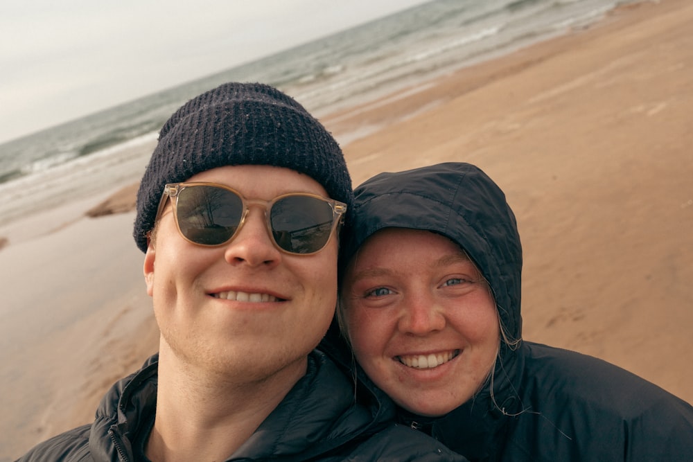 a man and a woman standing on a beach next to the ocean