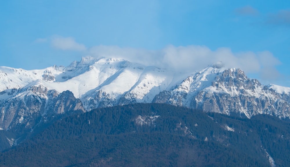 a mountain range covered in snow under a blue sky