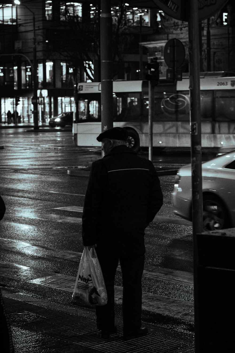 a man standing on the side of a street holding a bag