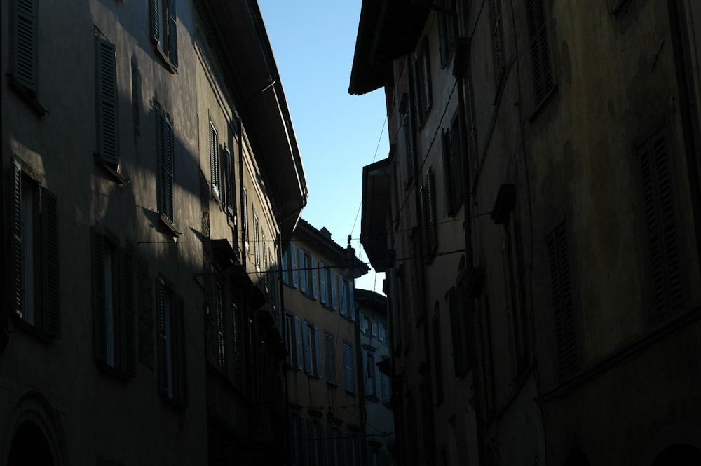a dark alley way with buildings and a blue sky in the background