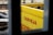 A bright yellow crate with empty brown glass bottles is partially visible through a window. The word 'CERVEJA' is printed in bold red letters on the side of the crate.