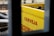 A bright yellow crate with empty brown glass bottles is partially visible through a window. The word 'CERVEJA' is printed in bold red letters on the side of the crate.