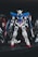 A detailed model of a Gundam robot, featuring a complex design with prominent colors of blue, white, and red. It is positioned upright with intricate mechanical features, standing on a dark surface with a blurred background.