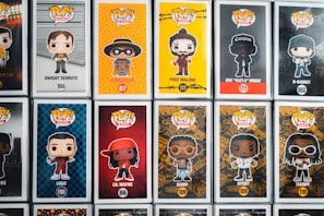 A collection of Pop! Vinyl figures displayed in their boxes, featuring various characters from television, music, and movies. Each box includes a cartoonish depiction of the character on a vibrant background, with their name and product number written below. The figures include characters like Dwight Schrute, Hamburlgar, Post Malone, Eazy-E, and others.