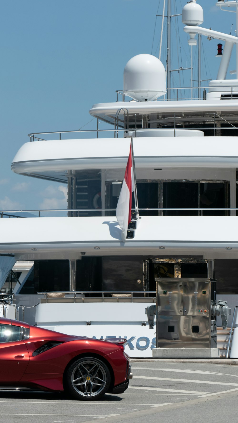 a red sports car parked in front of a yacht