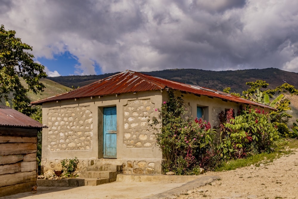 a small building with a rusty roof and a blue door