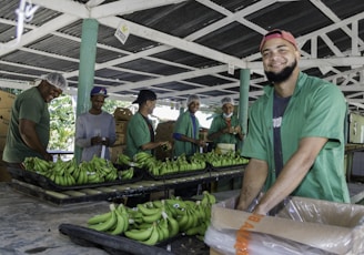 a group of men standing around a table filled with green bananas