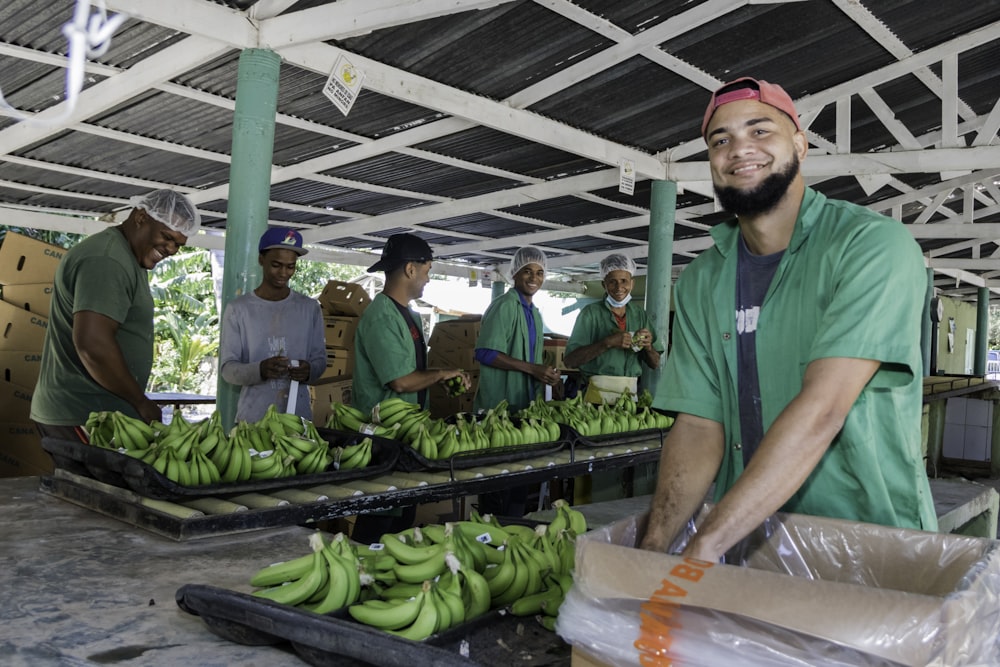 a group of men standing around a table filled with green bananas