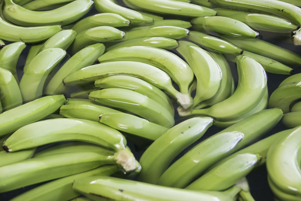 a pile of green bananas sitting next to each other
