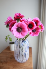 A close-up of vibrant plastic flowers arranged in a rustic vase on a wooden table.