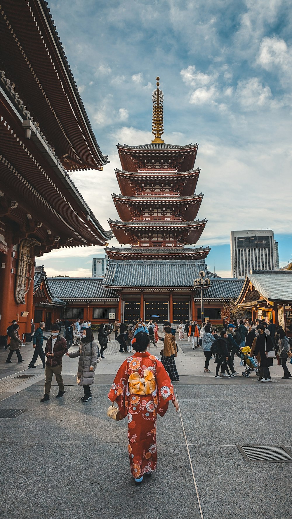 Una mujer con un kimono caminando frente a una pagoda