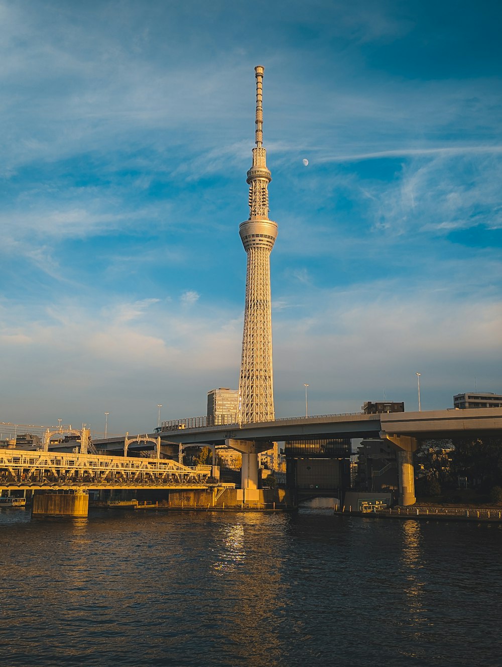 a tall tower towering over a river next to a bridge