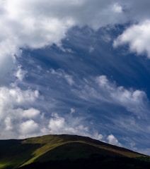 a large hill with some clouds in the sky