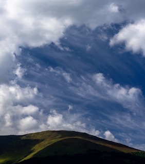 a large hill with some clouds in the sky