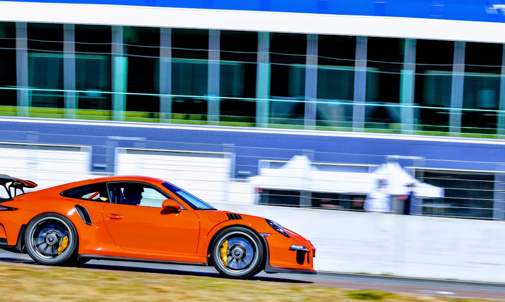 an orange sports car driving down a race track