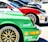 Several sports cars are lined up in a row, showcasing vibrant colors and sponsor logos. The forefront displays a green car with a detailed wheel rim and various brand decals, including Bosch and Shell. Each car features sleek designs, contributing to a dynamic and competitive atmosphere.