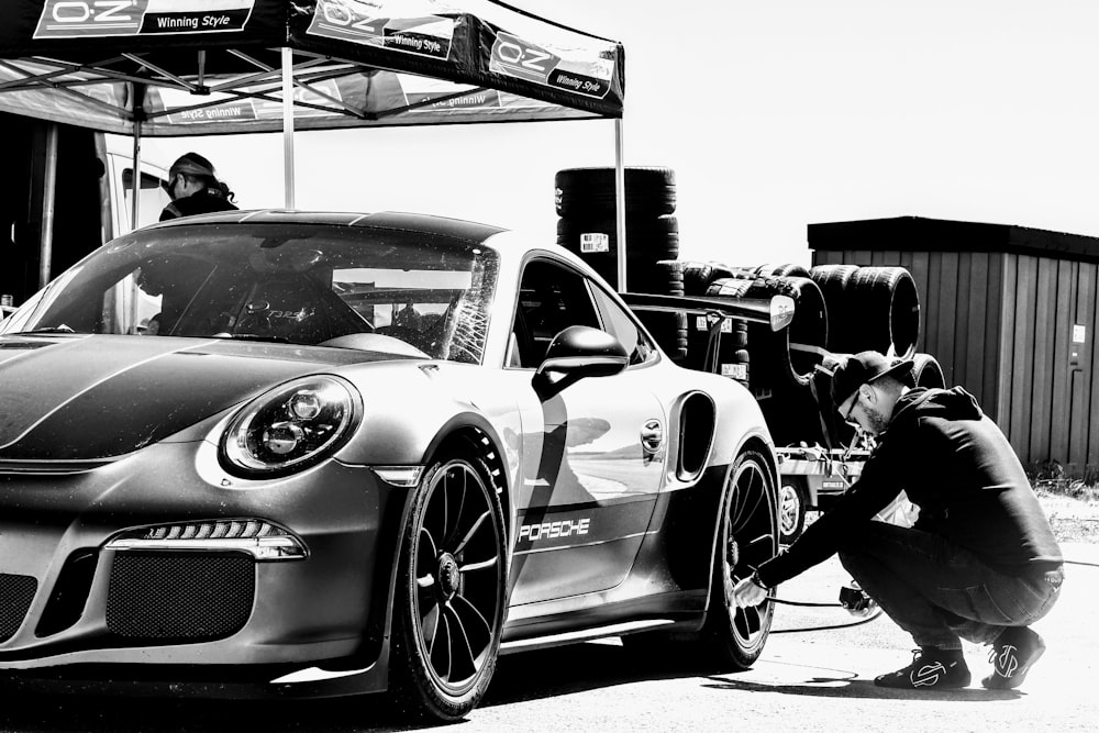 a black and white photo of a man working on a car