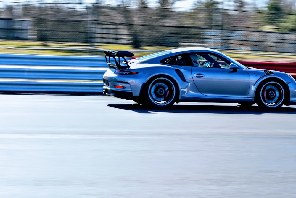 a blue sports car driving down a race track