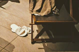 Soft white slippers placed beside a bathroom sink, part of the velours blanc guest kit.