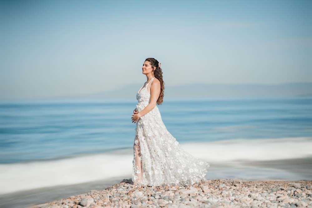 a pregnant woman standing on a rocky beach