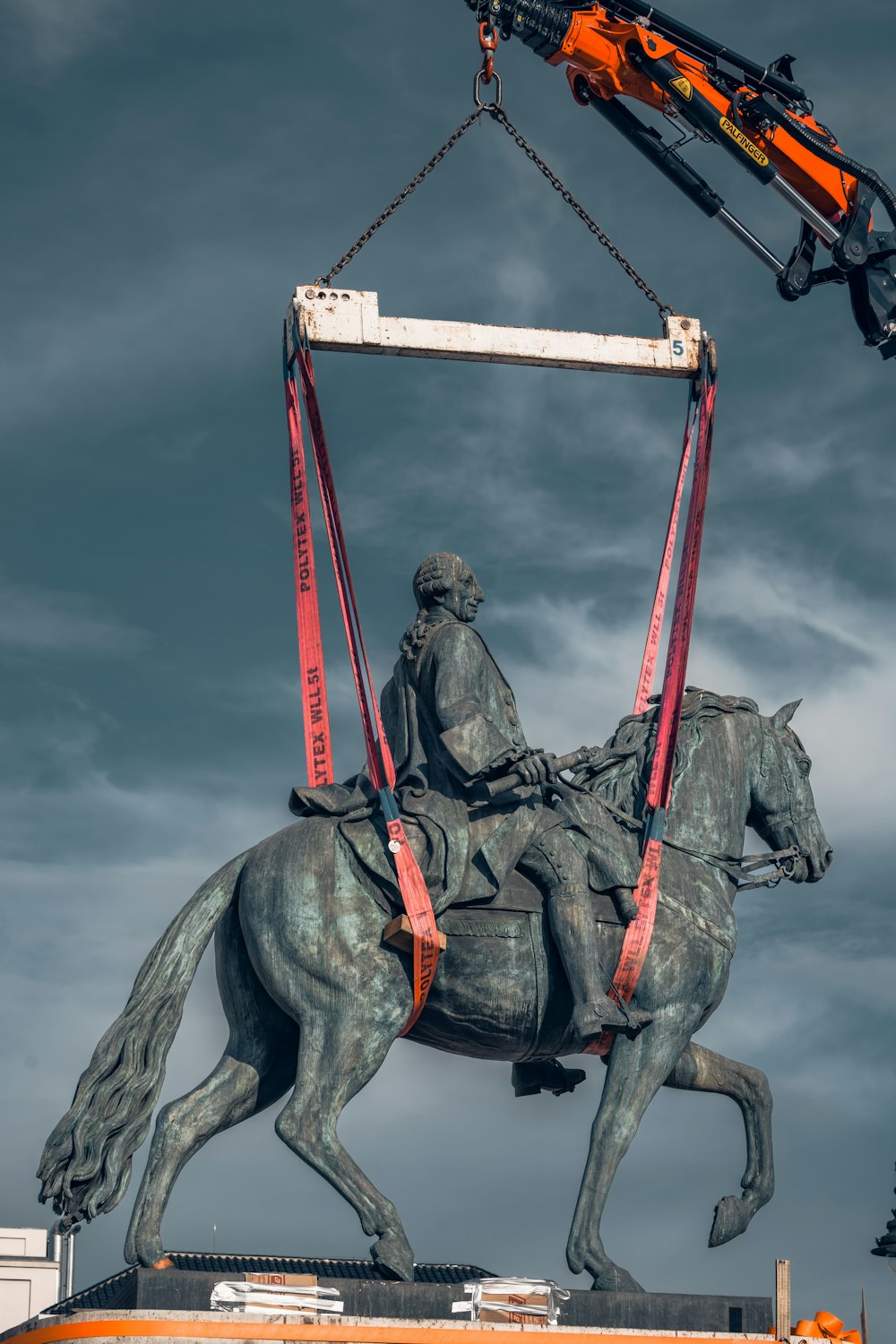 a statue of a man on a horse being lifted by a crane