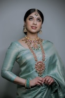 a woman wearing a green sari and jewelry