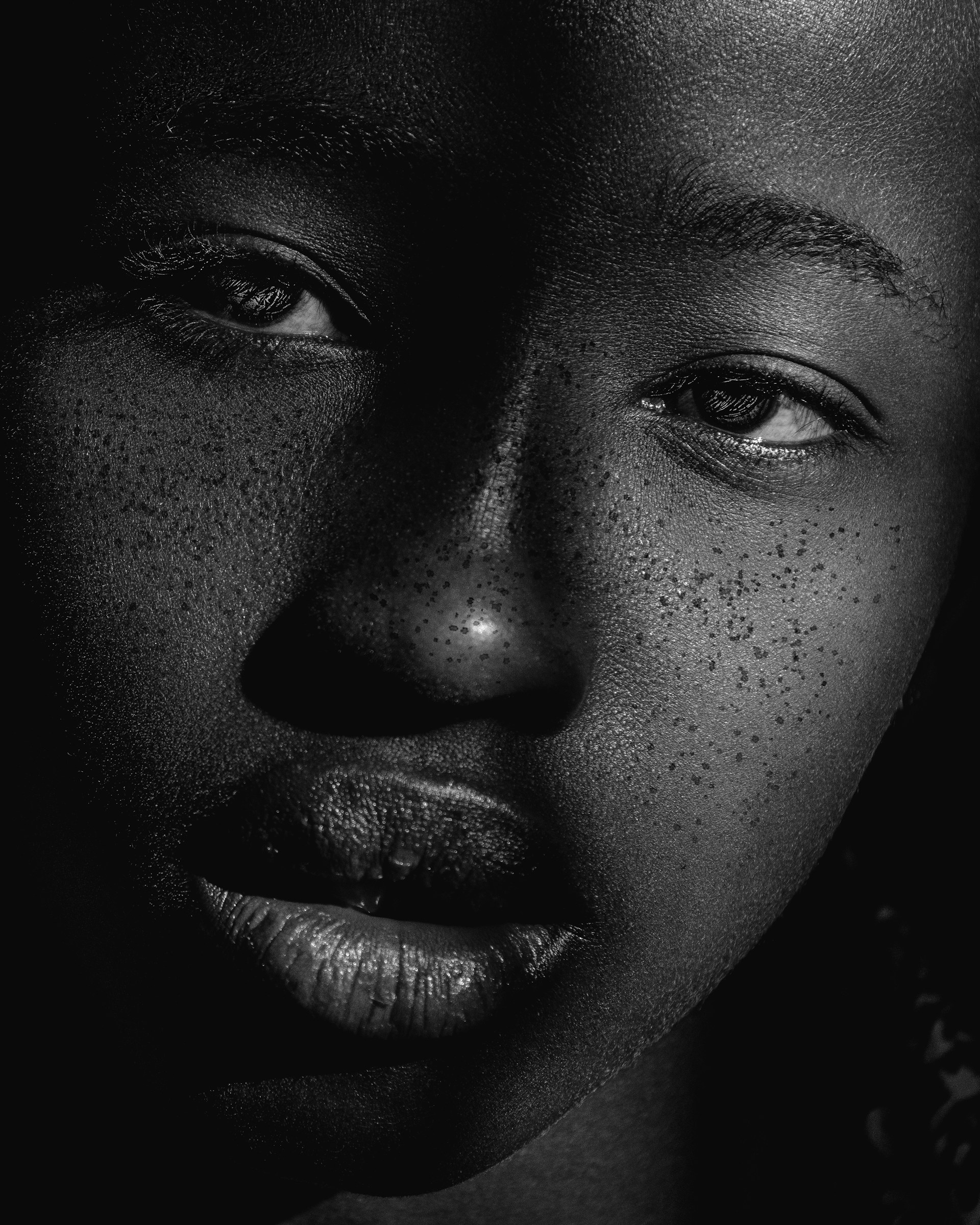 An intimate close-up of textured skin illuminated softly to reveal subtle details in monochrome.