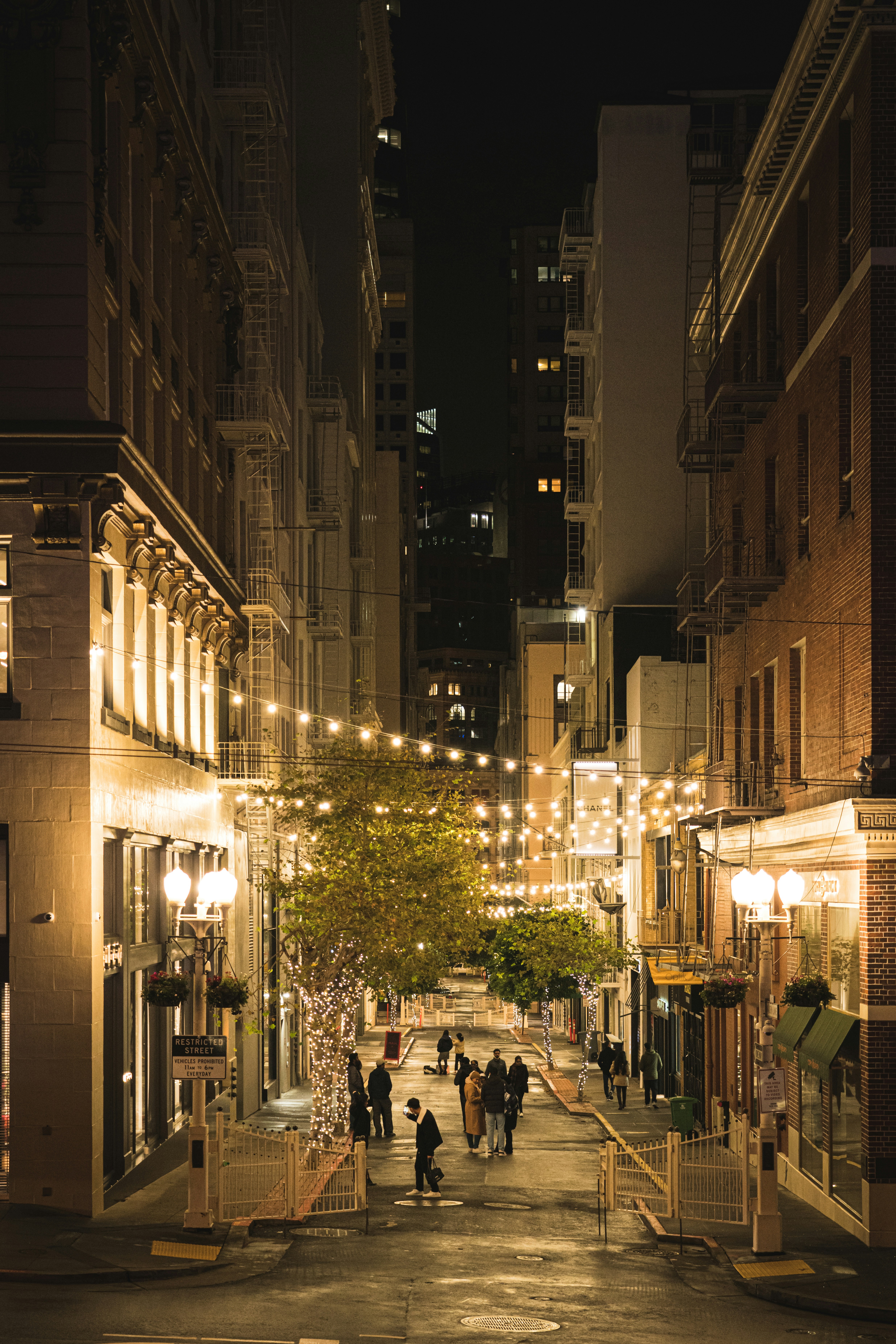 a group of people walking down a street at night