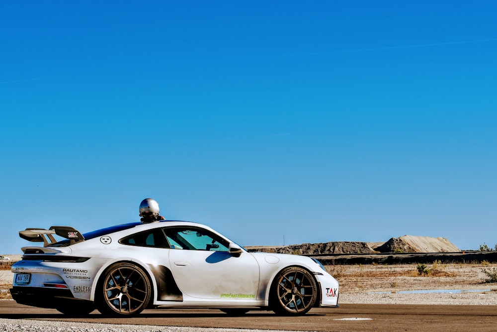 a white sports car driving down a road