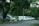 Several parked vehicles, including an ambulance, are lined up on the side of a road surrounded by lush greenery and trees. The vehicles appear to be stationary with some signs of wear.