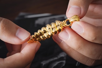a person is holding a gold chain with a clasp on it