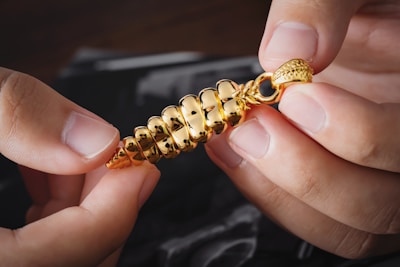 a person is holding a gold chain with a clasp on it