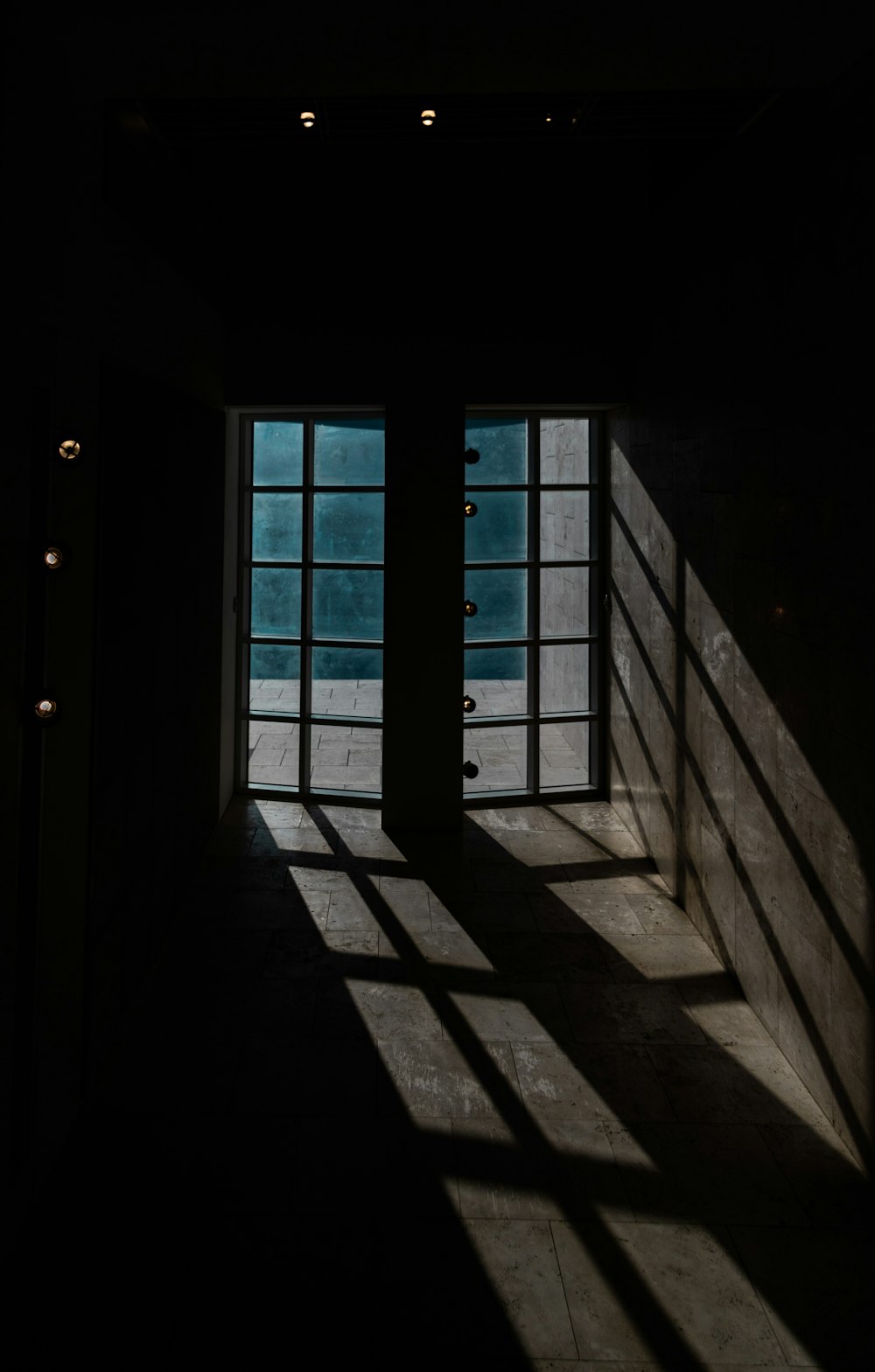 a dark room with two windows and a wall