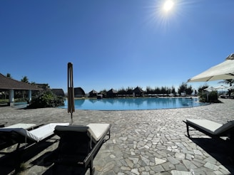 Bright outdoor pool with a partially covered solarium tarp under clear skies.