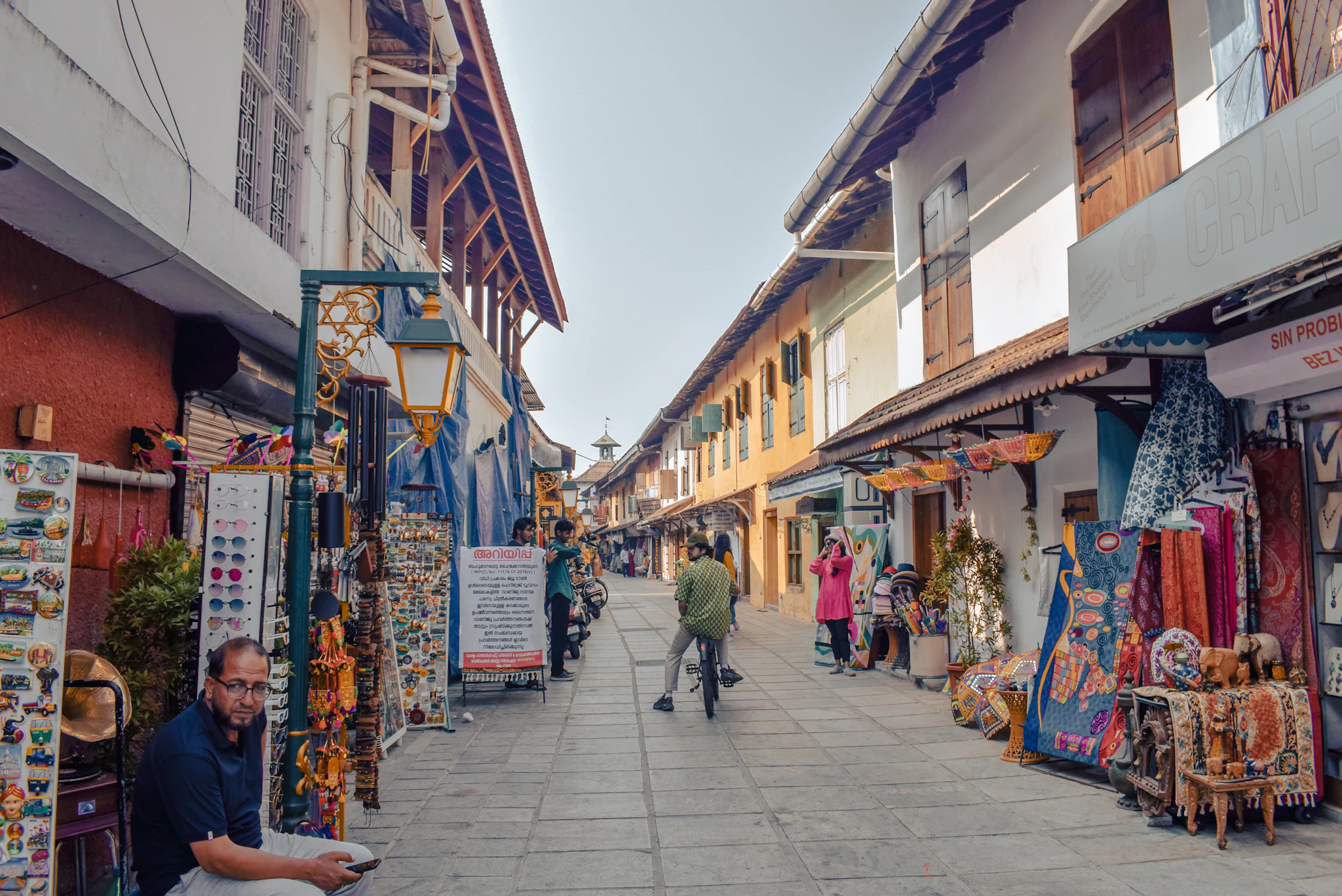 A man walking down a narrow street of small shops