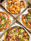 four pizzas with different toppings in a box