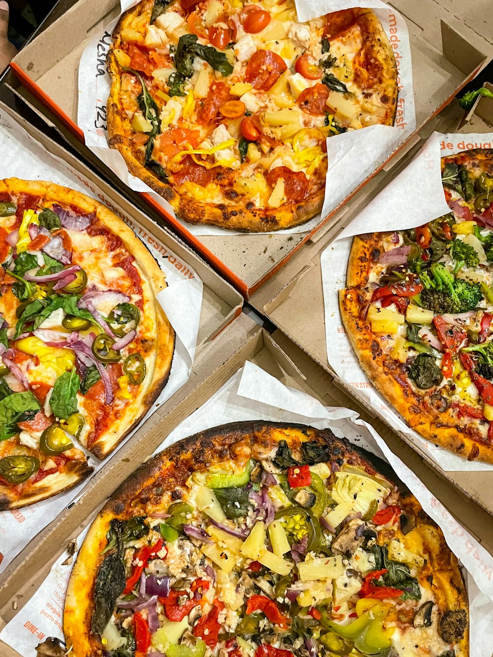 quatro pizzas com coberturas diferentes em uma caixa