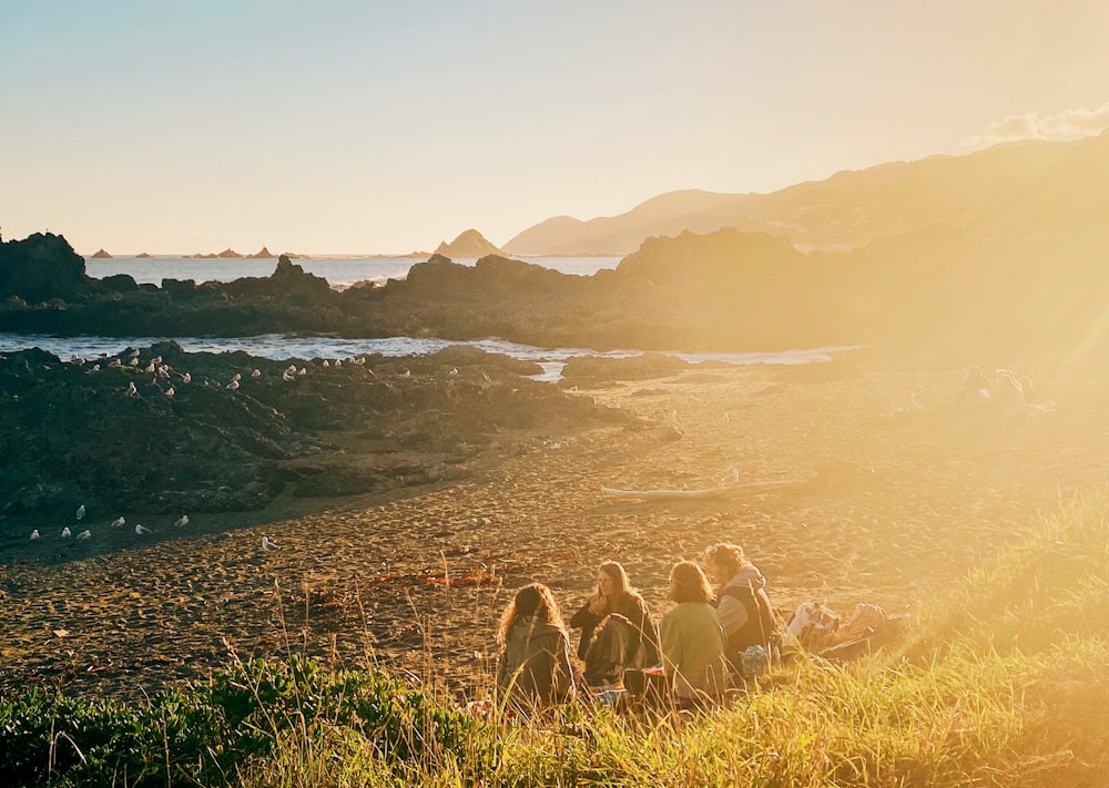 a group of people sitting on top of a lush green hillside