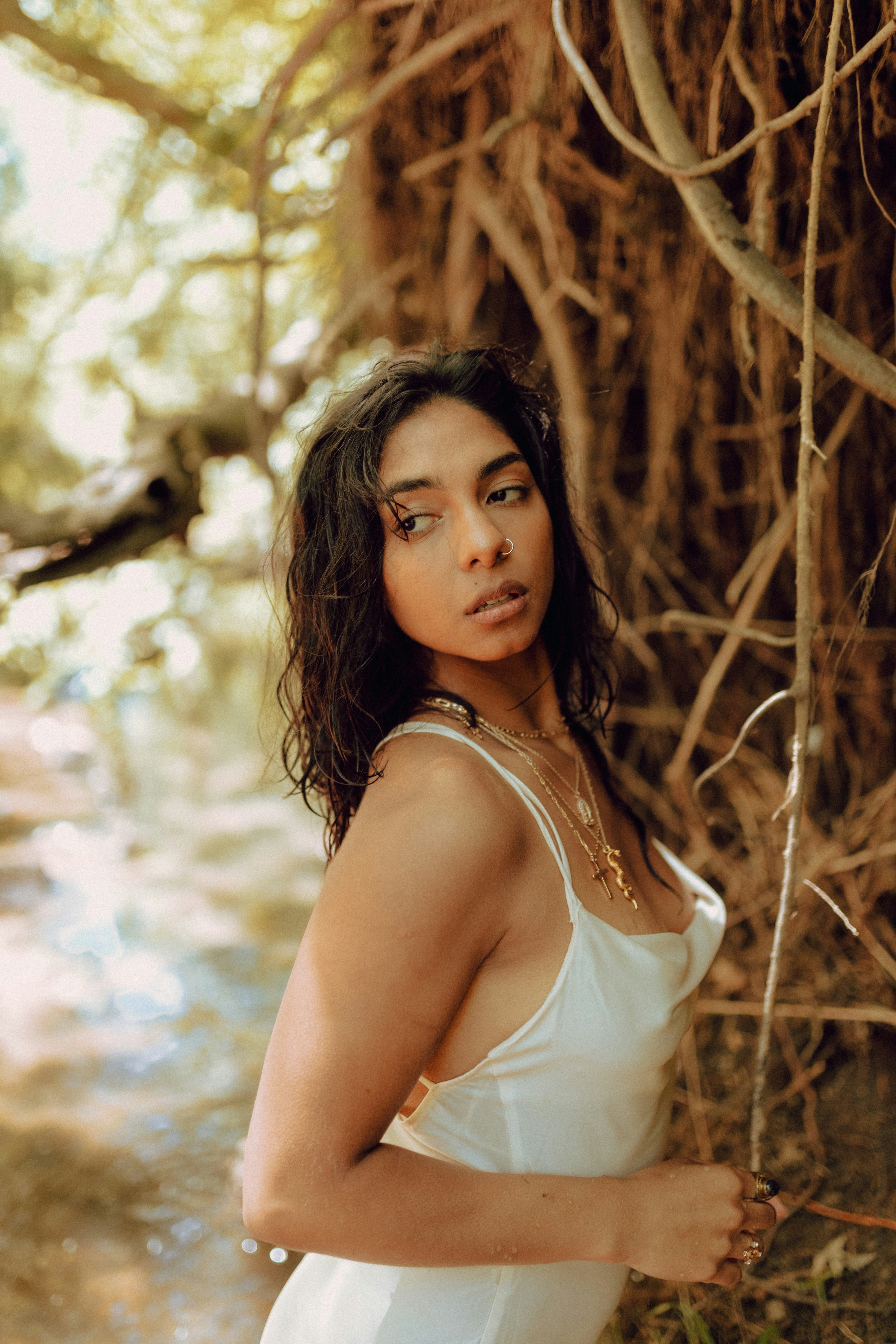 a woman in a white dress standing in front of a tree