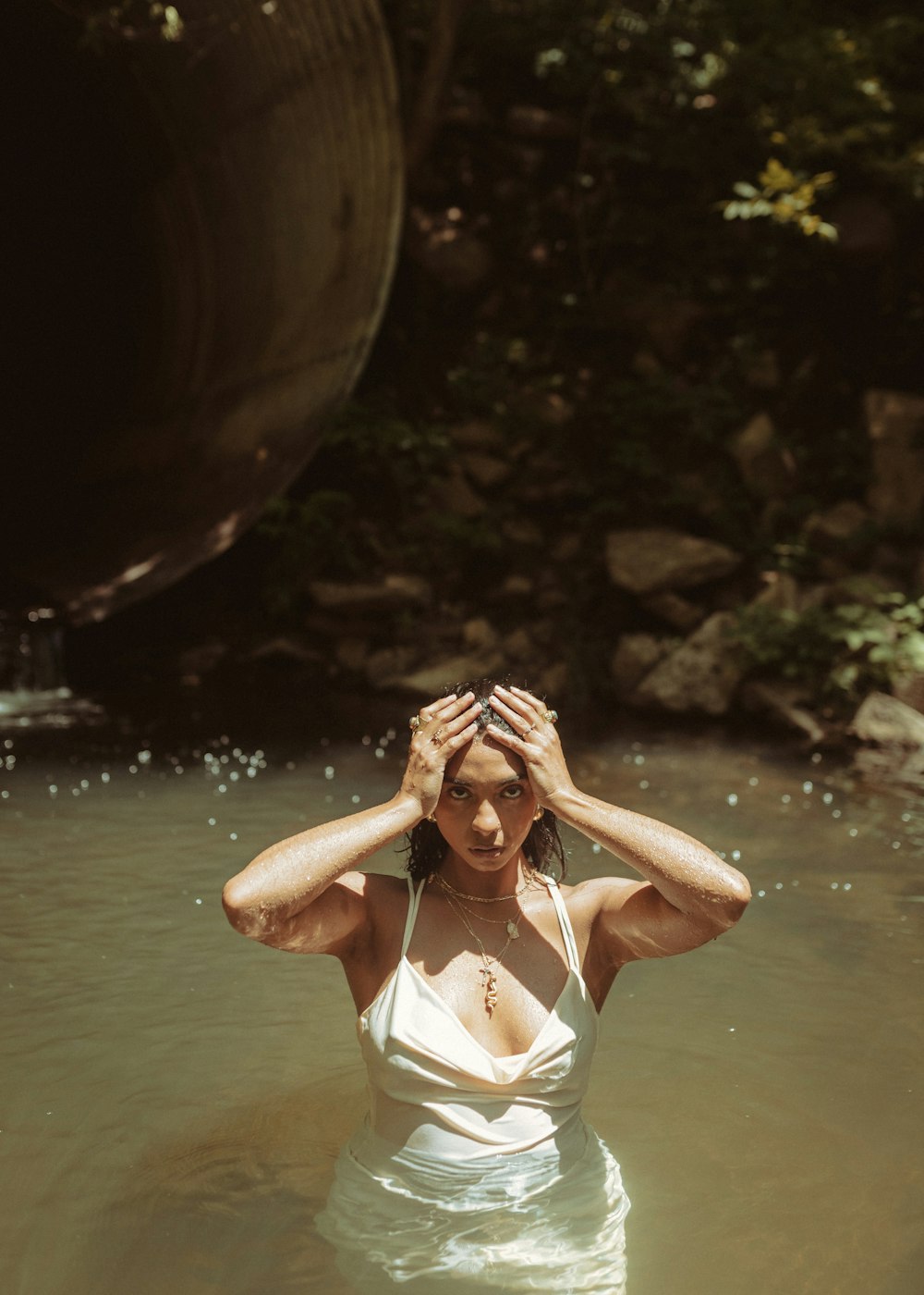 a woman standing in a body of water with her hands on her head
