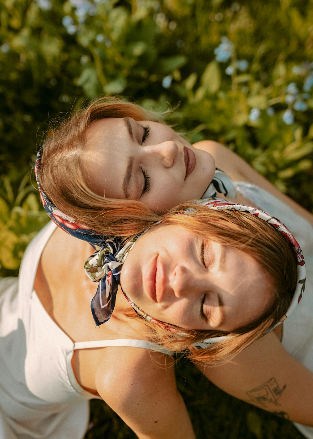 two women are laying down in the grass