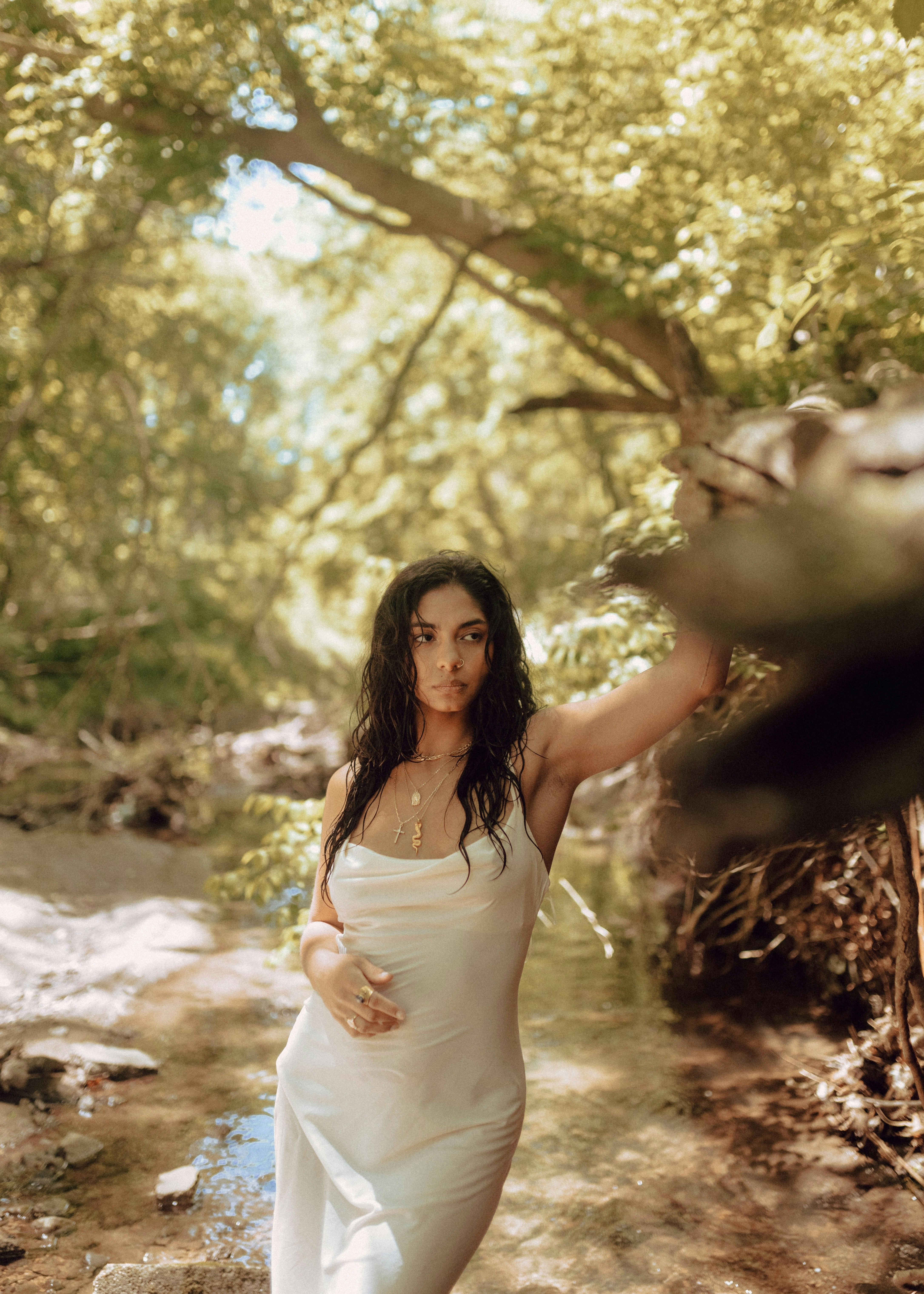 a woman in a white dress standing in a stream
