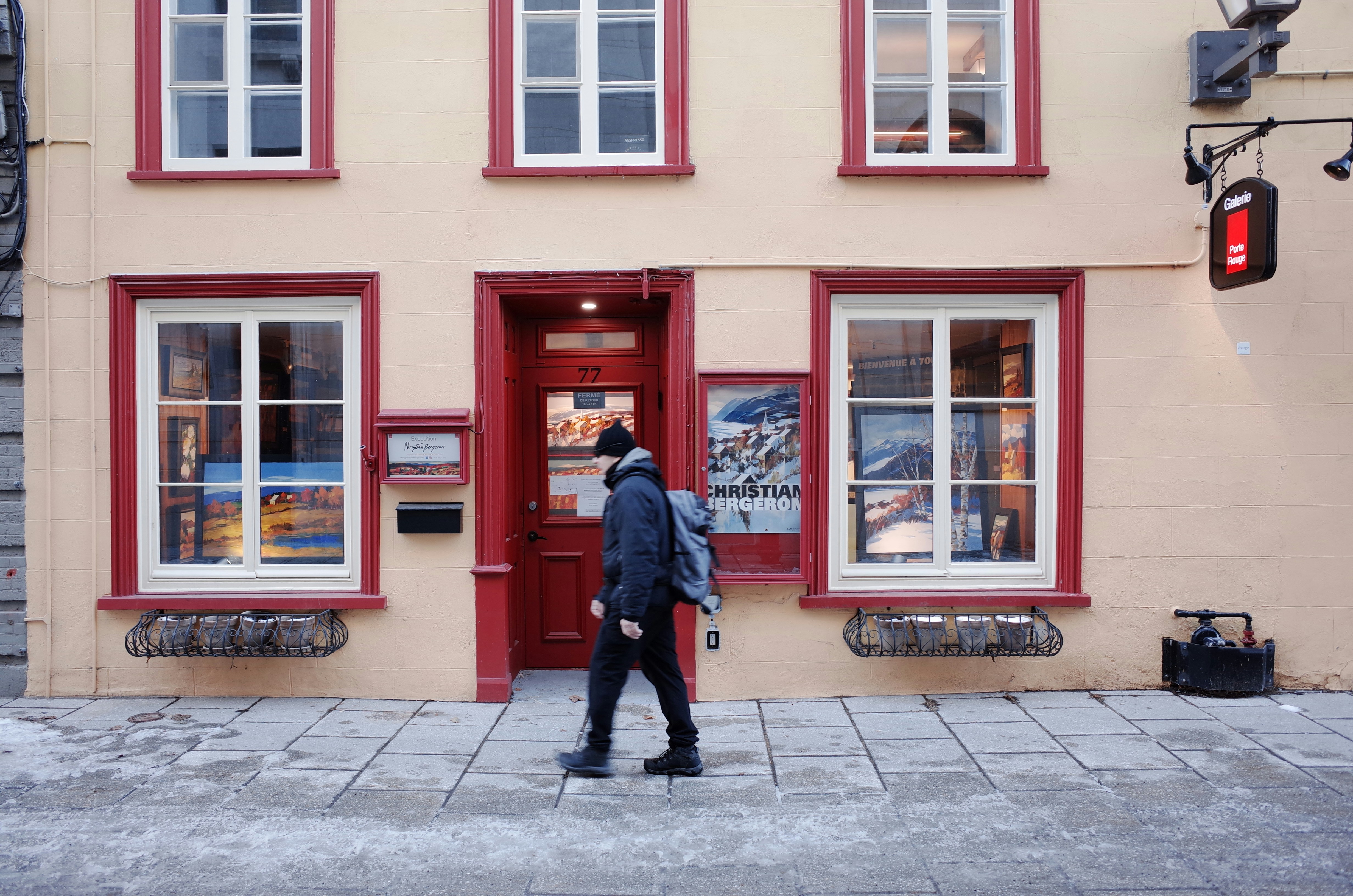 a man walking past a building with a red door