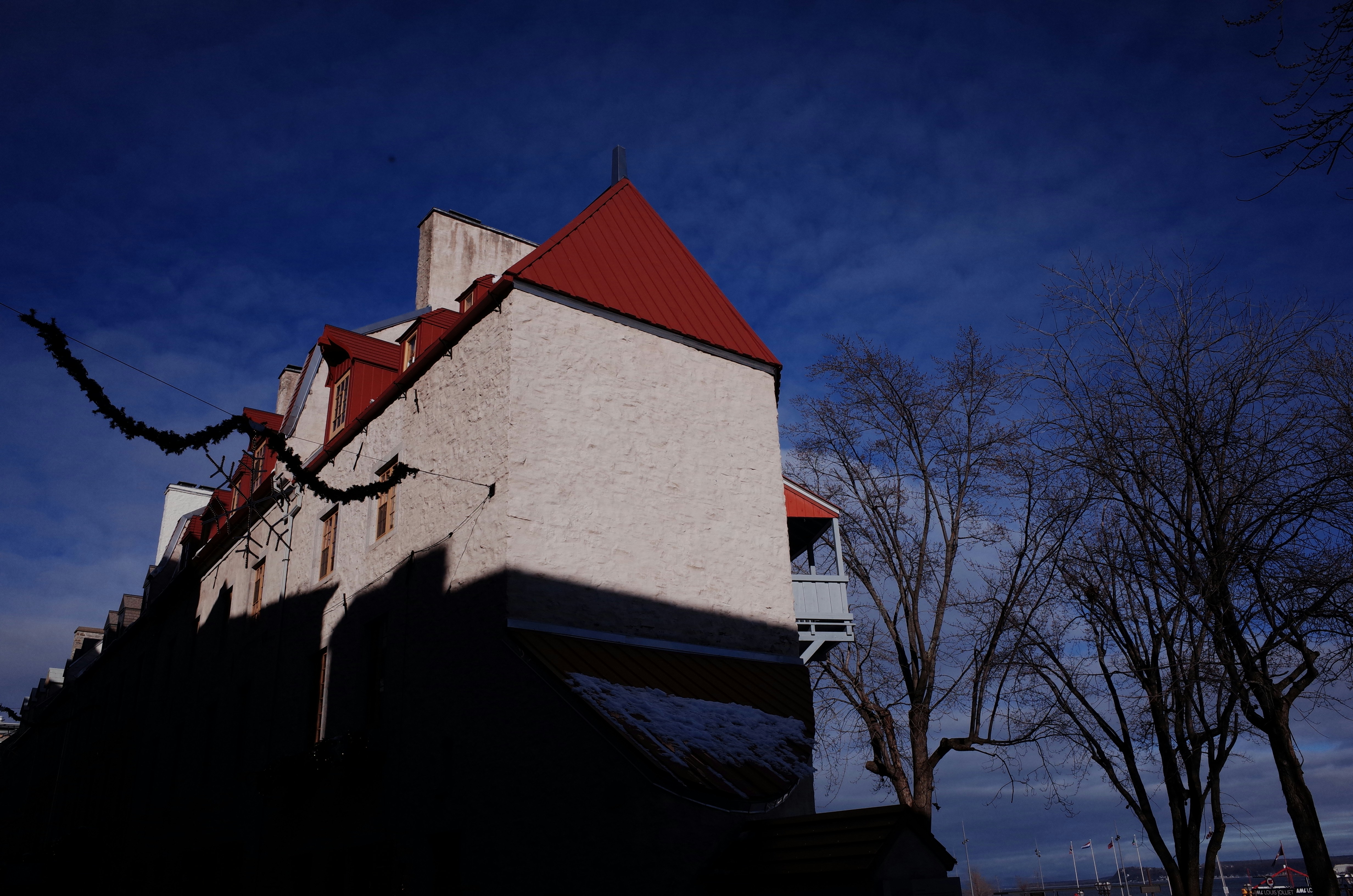 a white building with a red roof and a tree