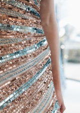 Close-up of a model wearing a shimmering sequin three-piece outfit in soft champagne gold.